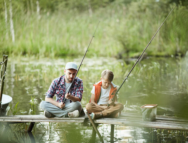 Ein Vater angelt mit seinem Sohn vom Steg aus Fische