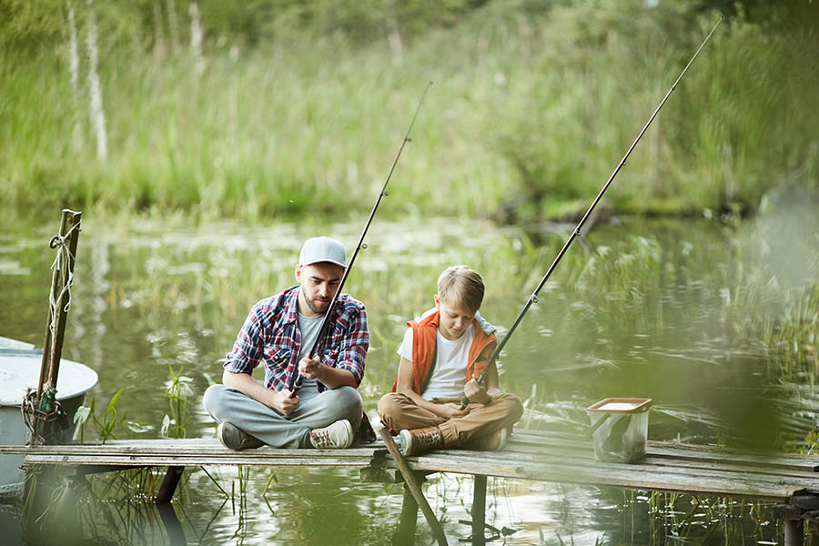Ein Vater angelt mit seinem Sohn vom Steg aus Fische